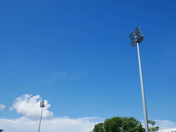Sports light pole or Stadium Light tower in sport arena on blue sky with clouds and copy space.
