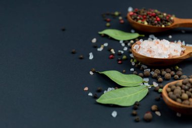 Kaba tuz ve biber baharat ile siyah bir arka plan ile üç tahta kaşıklar.