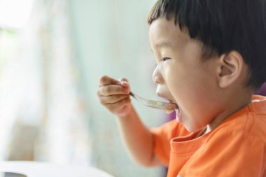 Çocuk kendi kepçelediği pirinçle ağzını açıyordu. Kendi başına yemek yemeyi öğreniyor..