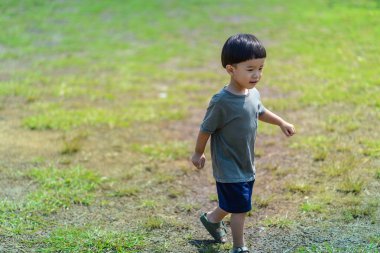 Küçük bebek çimenlerin üzerinde yürüyor. Açık hava öğrenimi gelişimine çok yardımcı olur..