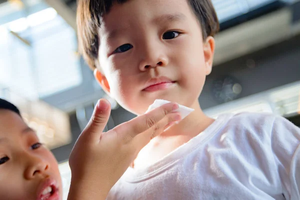 Kız kardeşi, çenesine hafifçe sildiği küçük kardeşiyle ilgileniyor. Pamuk yumağıyla küçük bir yara. Bunu sevgi ve özen yüzünden yaptı..
