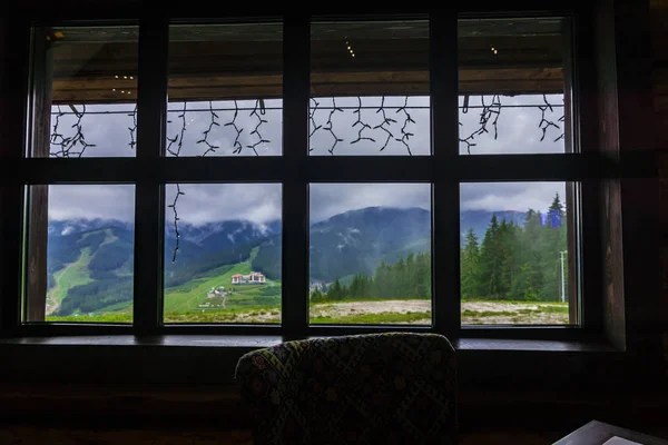 Cozy window view from warm wooden house in mountains at rainy day