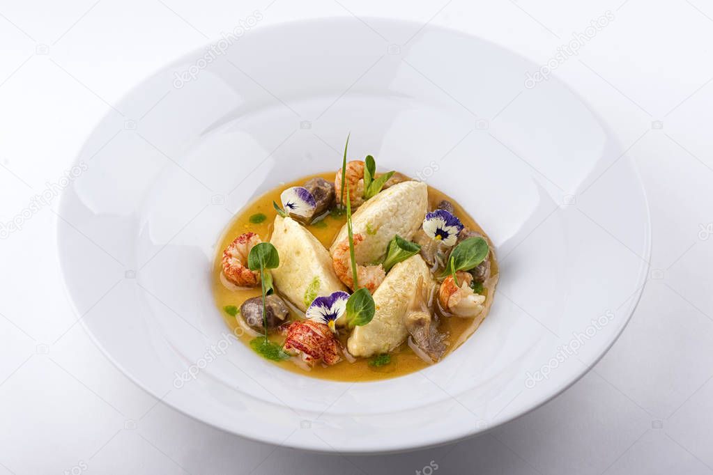 seafood dish garnished with edible flowers in plate on white background