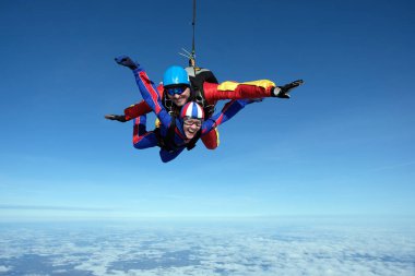 Tandem skydiving. Büyük adam ve bir kadın birlikte gökyüzünde uçuyor.