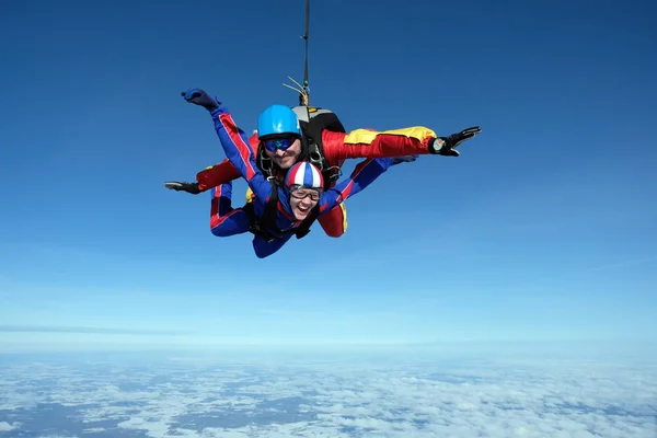 Tandem skydiving. Büyük adam ve bir kadın birlikte gökyüzünde uçuyor.