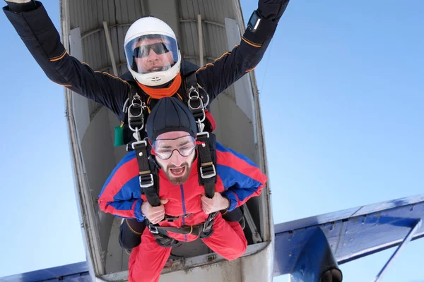 Tandem jump. Two men have just jumped out of am airplane. A passenger has a lot of emotions.