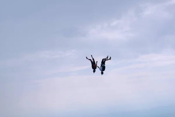 Serbest hava dalışı. İki paraşütçü bulutlu gökyüzünde uçuyor..
