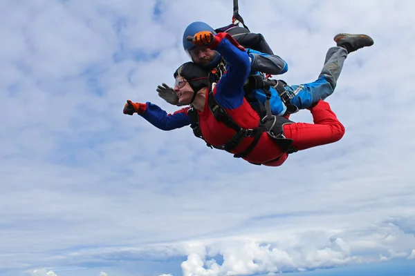 Tandem jump. Active woman and her strong instructor are falling in the sky together.