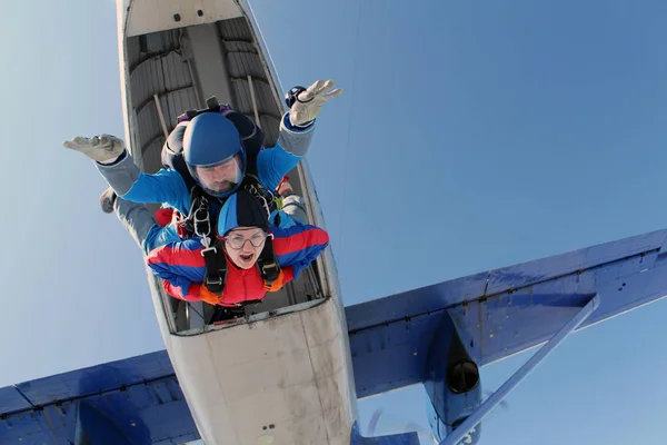 Tandem jump. Active woman and her strong instructor are falling in the sky together.