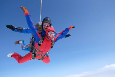 Skydiving. Tandem atlayışı. Güçlü bir adam ve genç bir kadın gökyüzünde uçuyorlar..