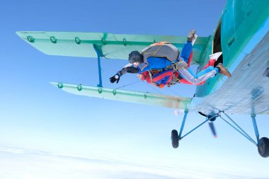 Skydiving. Tandem atlayışı. Güçlü bir adam ve genç bir kadın gökyüzünde uçuyorlar..