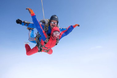 Skydiving. Tandem atlayışı. Güçlü bir adam ve genç bir kadın gökyüzünde uçuyorlar..