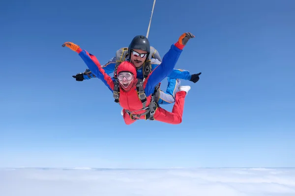 Skydiving. Tandem atlayışı. Güçlü bir adam ve genç bir kadın gökyüzünde uçuyorlar..