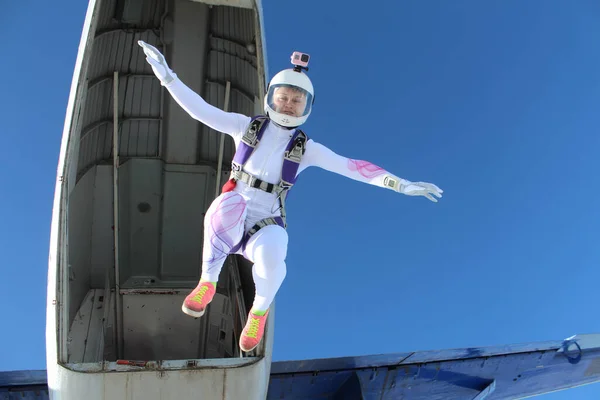 Skydiving. A beautiful girl has just jumped out of a plane into the blue sky.