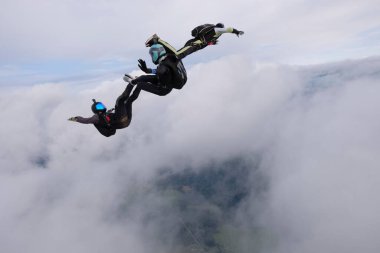 Hava dalışı. Bulutlu gökyüzüne üç paraşütçü düşüyor.
