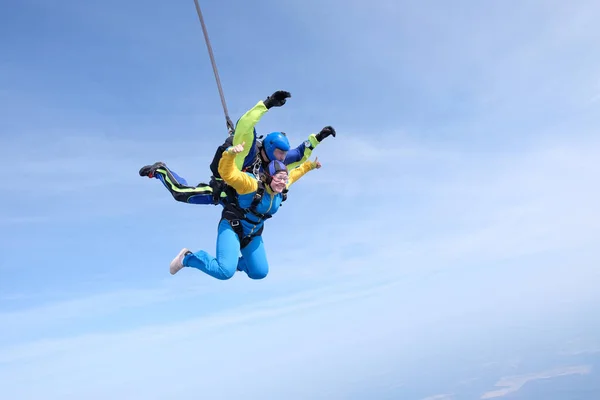 Skydiving. Tandem jump. A woman and her instructor are flying in the blue sky.