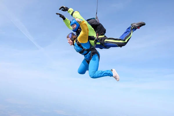 Skydiving. Tandem jump. A woman and her instructor are flying in the blue sky.