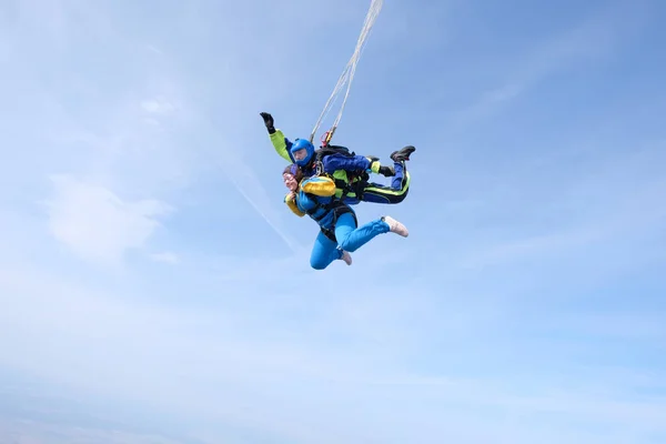 Skydiving. Tandem jump. A woman and her instructor are flying in the blue sky.