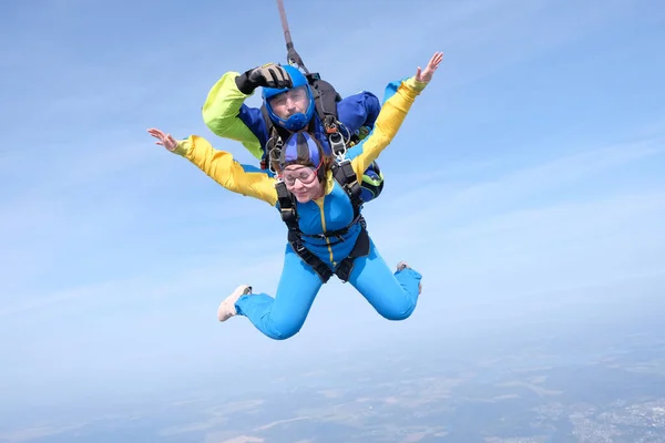 Skydiving. Tandem jump. A woman and her instructor are flying in the blue sky.