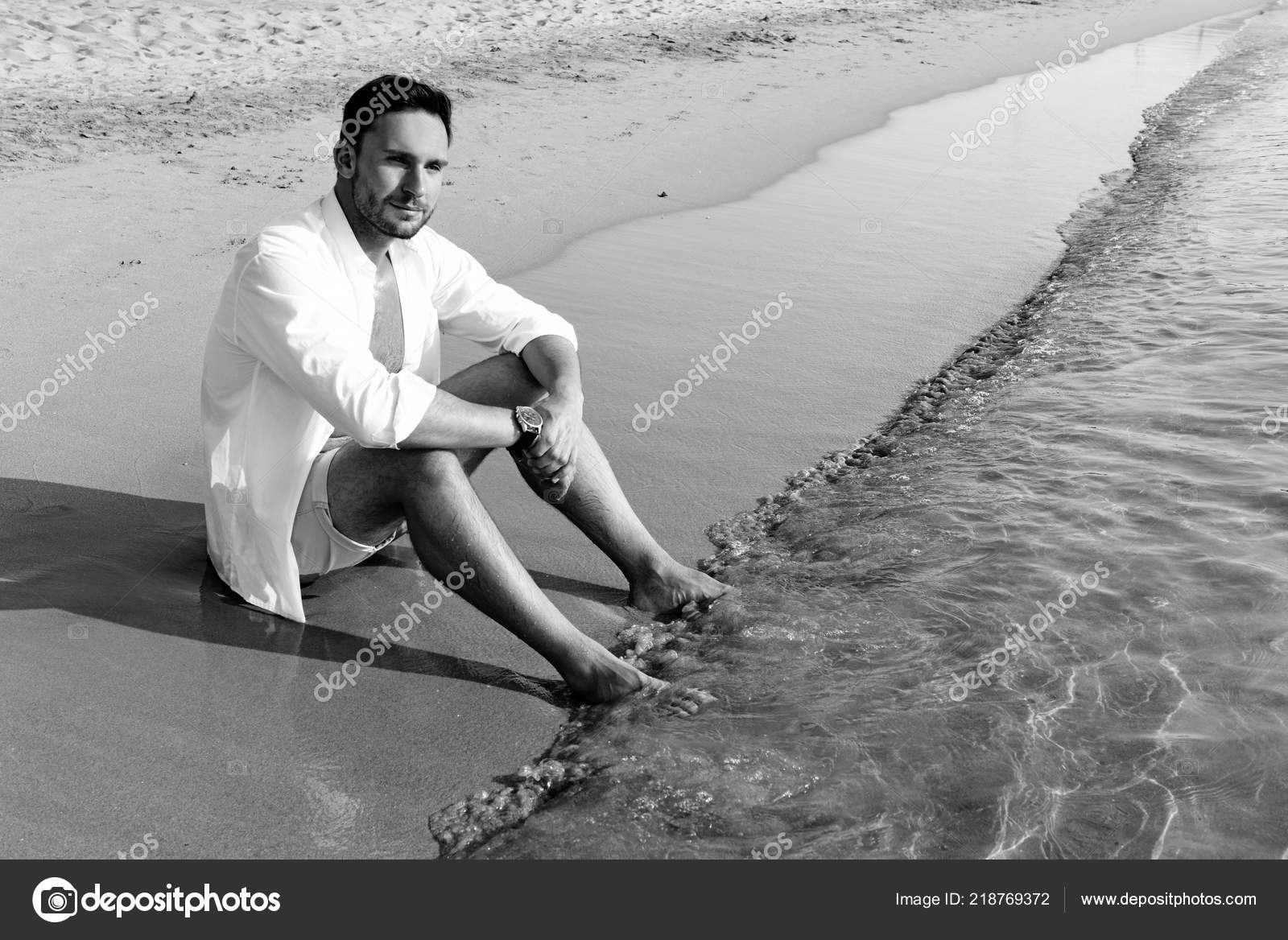 Handsome man in white shirt standing on a beach seaside looking hot on  summer day enjoying
