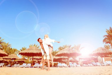 Güzel genç çift el ele tutuşarak, sarılma ve alma selfies güneşli bir plaj tatil sahip. Mutlu yakışıklı adam ve beyaz gömlek öpüşme sırasında ve sırtıma Hawaii'ye seyahat zevk sarışın kadın