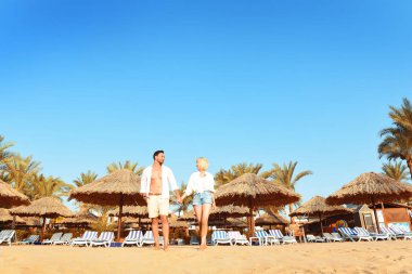Güzel genç çift el ele tutuşarak, sarılma ve alma selfies güneşli bir plaj tatil sahip. Mutlu yakışıklı adam ve beyaz gömlek öpüşme sırasında ve sırtıma Hawaii'ye seyahat zevk sarışın kadın