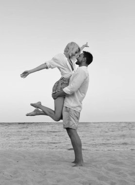 güzel çift hawaii tatil plaj manzarası arıyorum onların tadını seviyorum. Sevimli sarışın kadın ve sakallı yakışıklı bir kum sarılma üzerinde ayakta, el ele tutuşarak, deniz tarafında izlerken beyaz gömlek içinde.