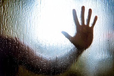 naked man in the shower holding hands against the glass wall, a sign of depression, loneliness and sadness. His hand rests on a glass partition with a drops of water. clipart