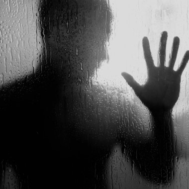 el ele tutuşarak cam duvar, depresyon, yalnızlık ve hüzün bir işareti karşı duşta çıplak adam. Bir cam bölme su damlaları ile onun elini dayanmaktadır.