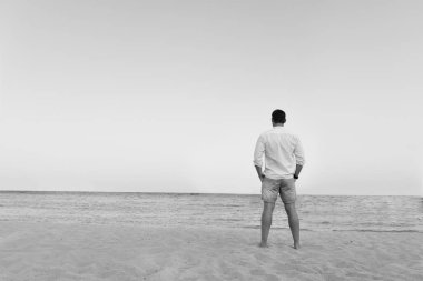 Yakışıklı adam beyaz gömlek daimi bir plajda yaz günü hayattan zevk sıcak bakıyor. Vahşi erkek model su çıplak Göğüs dışarı, sırıtma üzerinde görünüm ve tarz gözleri ile gülümseyen ıslak kısa ile poz veriyor.