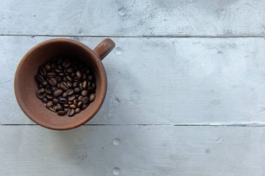 mavi ahşap bir masa üzerinde bir kahverengi kahve Kupası'nda ham ve kavrulmuş kahve çekirdekleri