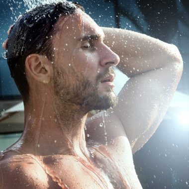 Genç iyi görünümlü ve kas vücut ıslak alarak duş, banyo ile çekici bir adam. yakışıklı çekici erkek yüzme havuzu yanında duş. su damlaları onun Gövde üzerinde düşüyor