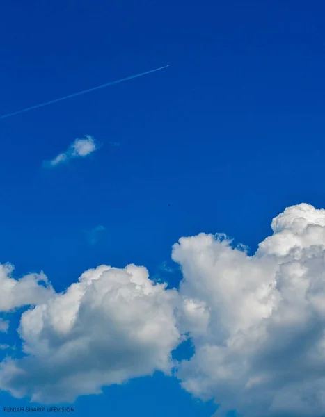 Plane in the Sky. White Line in the Sky. Clouds and Skyscapes. Airplane in the sky with clouds