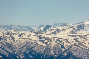 Bulutlar mavi gökyüzü altında orman arka planı bahar kar ve buz çözme ile bir dağ yamaçlarında. 