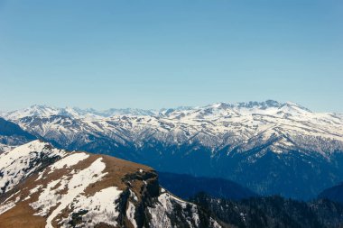 Bulutlar mavi gökyüzü altında orman arka planı bahar kar ve buz çözme ile bir dağ yamaçlarında. 