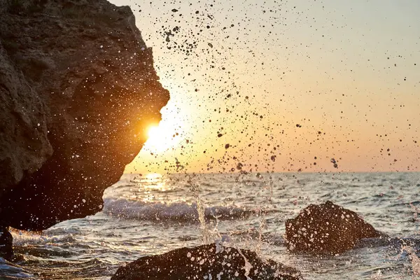 Günbatımı deniz kenarında. Altın kumlar. Dalgalar deniz kumları ve kayalar üzerinde rulo.                               