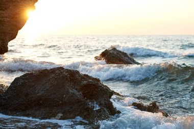                Splash dalgalar güzel gün batımı ve gökyüzü ile kayalara çarptı                