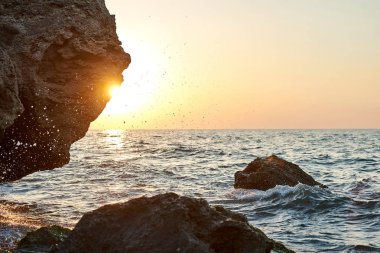 Günbatımı deniz kenarında. Altın kumlar. Dalgalar deniz kumları ve kayalar üzerinde rulo.