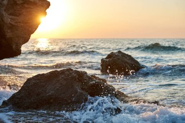               Günbatımı deniz kenarında. Altın kumlar. Dalgalar deniz kumları ve kayalar üzerinde rulo.                 