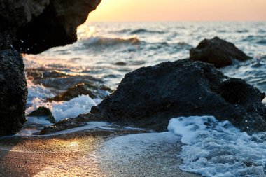 Splash dalgalar güzel gün batımı ve gökyüzü ile kayalara çarptı                               