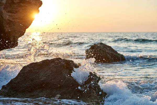                          Splash dalgalar güzel gün batımı ve gökyüzü ile kayalara çarptı      