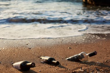 Buz gibi bir şişe altın kumun üzerinde dikiliyor. Yaz akşamı, Kırım, Ukrayna 06.10.2018