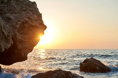 Günbatımı deniz kenarında. Altın kumlar. Dalgalar deniz kumları ve kayalar üzerinde rulo.                              