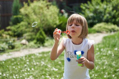 Küçük kız sabun köpüğü üflüyor