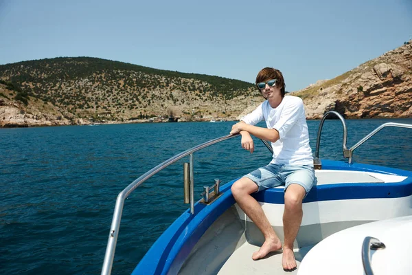 Portrait of a young successful man on the background of sky and sea landscape.  with glasses in white shirt leaning on the railing of the ship. Cruise.