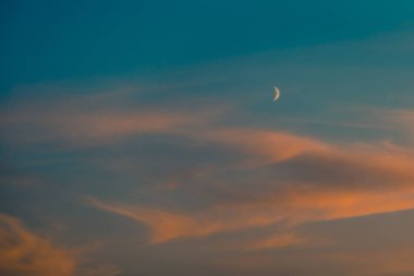 Akşam gökyüzünde hilal şeklinde ay bulutları ile örtülü
