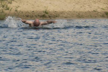 Bir kıyıdan diğerine nehrin bir adam kelebek yüzüyor