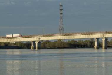 Geniş bir nehrin karşısındaki demir kemerli otomobil köprü