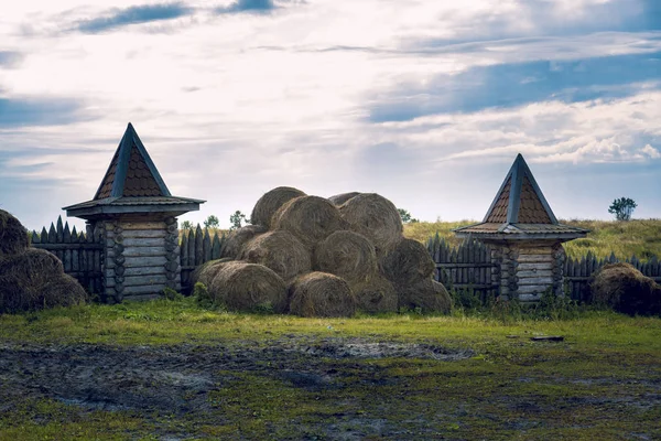 On the manor fenced with a palisade with watchtowers lie bales of hay