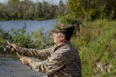 Nehir kıyısında bir sigara balıkçı ortalama planı iplik atıyor